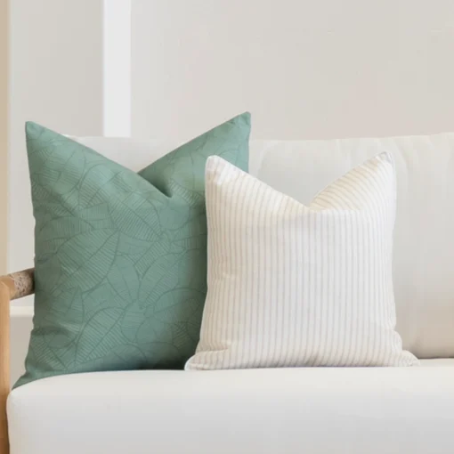 A set of avena outdoor cushions tucked in the corner of a white sofa.