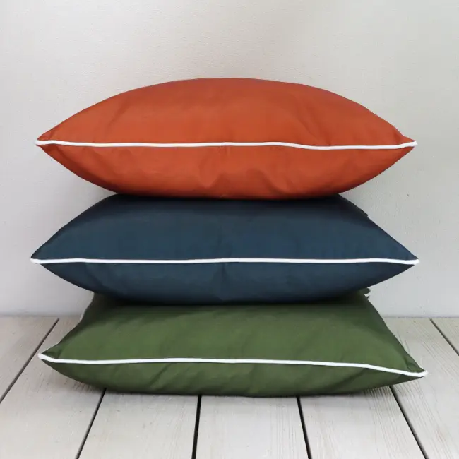 A balanced arrangement of large outdoor cushions showing their white piping.