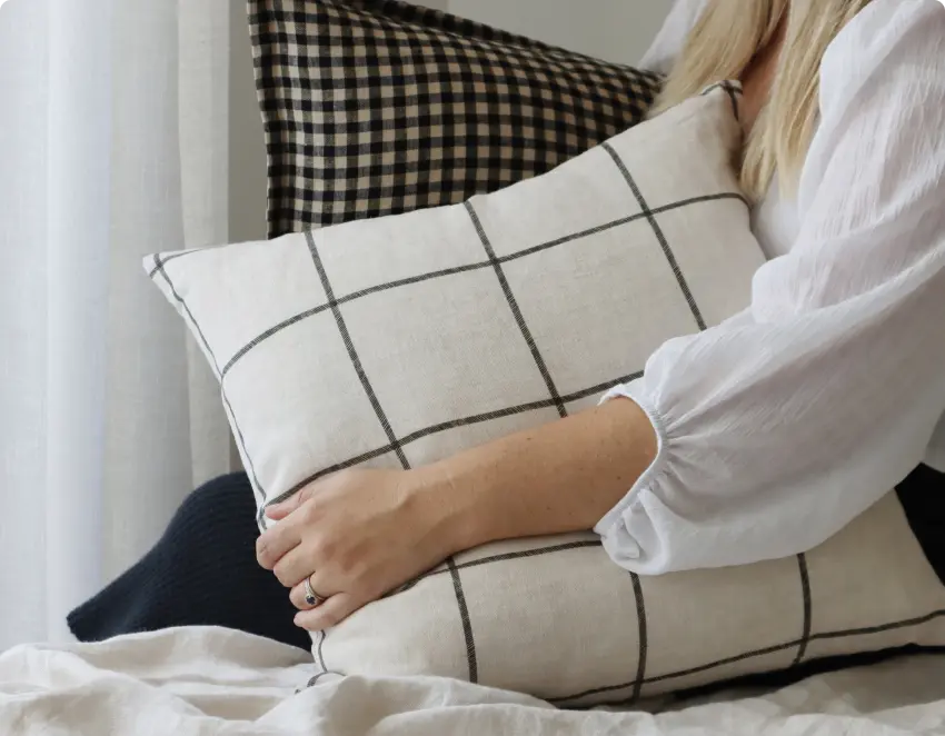 A bed scene is shown with a lady holding two premium contrasting cushions.