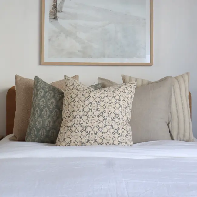 A bedding scene shows a group of large cushions below some wall art.