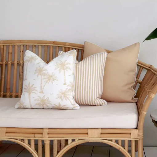 Three beige outdoor couch cushions arranged at the end of a rattan seat.