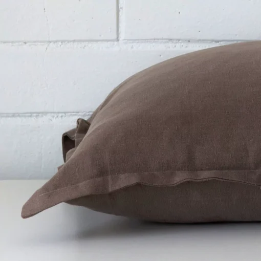 Large cushion in chocolate brown colour laying flat. The viewpoint highlights the seams of the linen fabric.