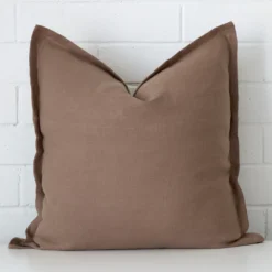 A bold linen cushion in a sleek large size with a clay tone of colour.