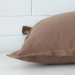 A side shot of a linen cushion cover. The angle shows the edge of the large shape and the clay tone.