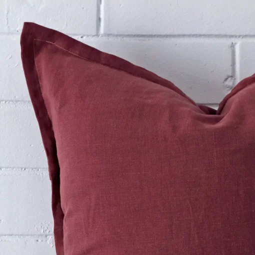 Extreme close up of a large plum cushion. The linen fabric is shown with a much higher degree of detail.