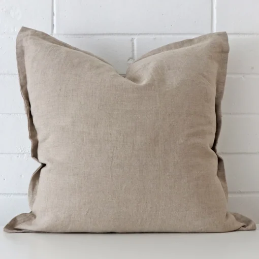 Here a stone linen cushion is shown styled against a white wall. It has a large design.