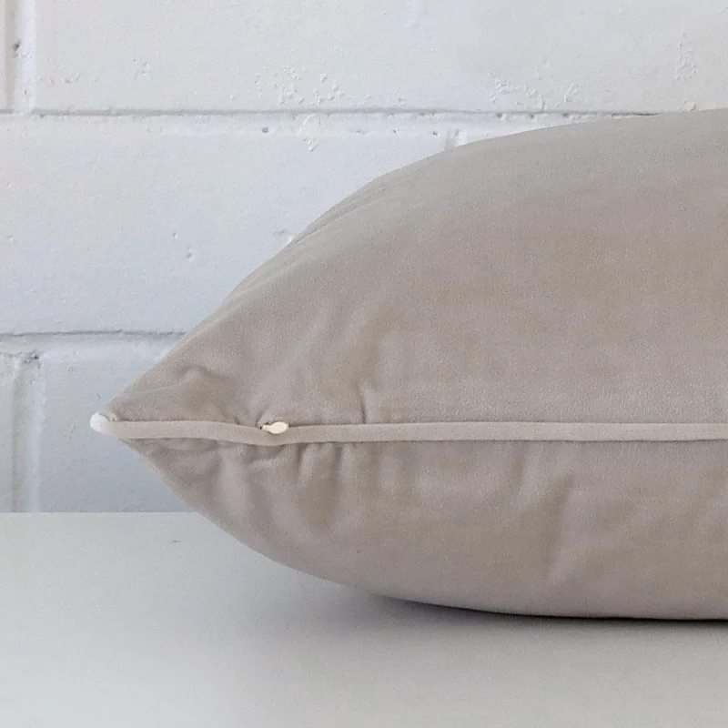A large grey cushion cover laying flat. This viewpoint highlights the velvet fabric from a side position.
