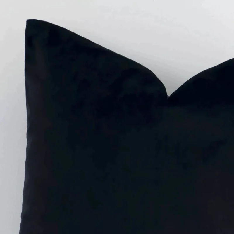 This image shows a black solid colour cushion cover from a very close range. The square size and velvet material are more clearly shown.