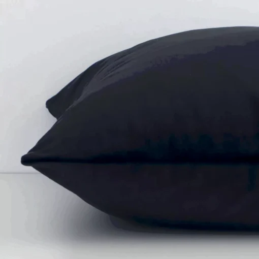 A close up image of this solid-coloured square cushion. The image shows details of its velvet fabric and black colour.