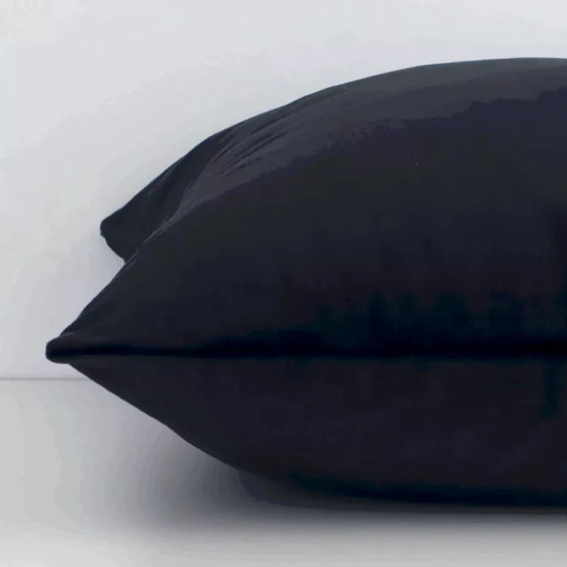 A close up image of this solid-coloured square cushion. The image shows details of its velvet fabric and black colour.