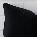 A close up image of this rectangle cushion. The image shows details of its velvet fabric and black colour.