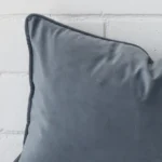 This image shows a blue grey cushion cover from a very close range. The rectangle size and velvet material are more clearly shown.