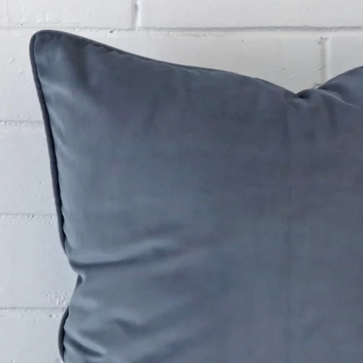 Extreme close up of a large blue grey cushion. The velvet fabric is shown with a much higher degree of detail.