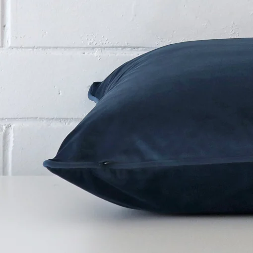 Large cushion in blue colour laying flat. The viewpoint highlights the seams of the velvet fabric.