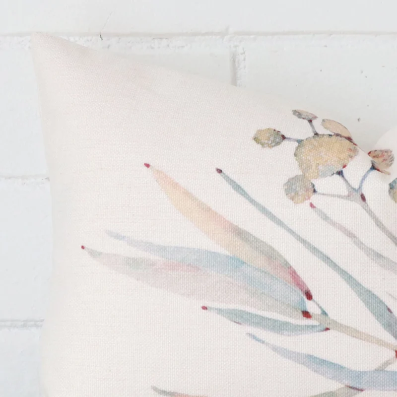 A zoomed in photo of the corner of a floral cushion that has linen fabric and a rectangle size.