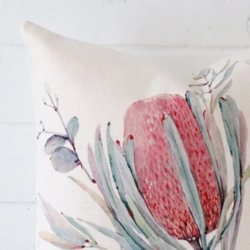 Close up of a linen square cushion. The quality of its floral design is shown in fine detail.