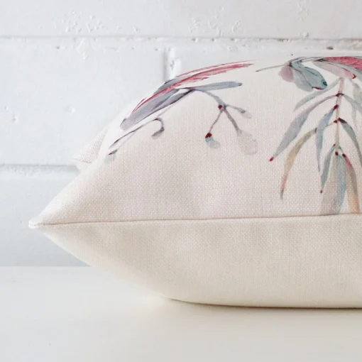 A floral cushion cover is laid flat. This angle shows the side of the linen fabric and its square shape.