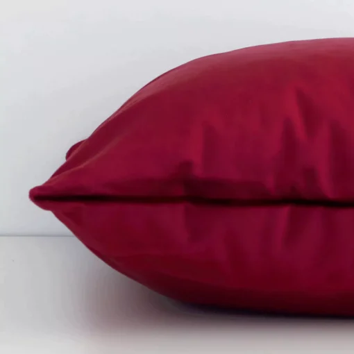 Side image of a velvet rectangle cushion cover. The solid burgundy colour design is visible from the side showing the attachment of the panels.