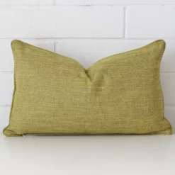 A rectangle cushion in a delightful olive tone rests against a white wall. The linen material appears to be of exceptional quality.