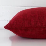 Horizontal edge of square cushion cover is shown. The linen fabric and maroon can be seen from this side view.