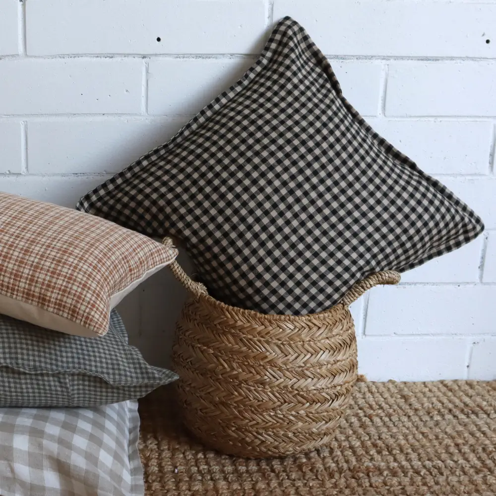 A cane container is supporting a Lithuanian Linen cushion from its corner.