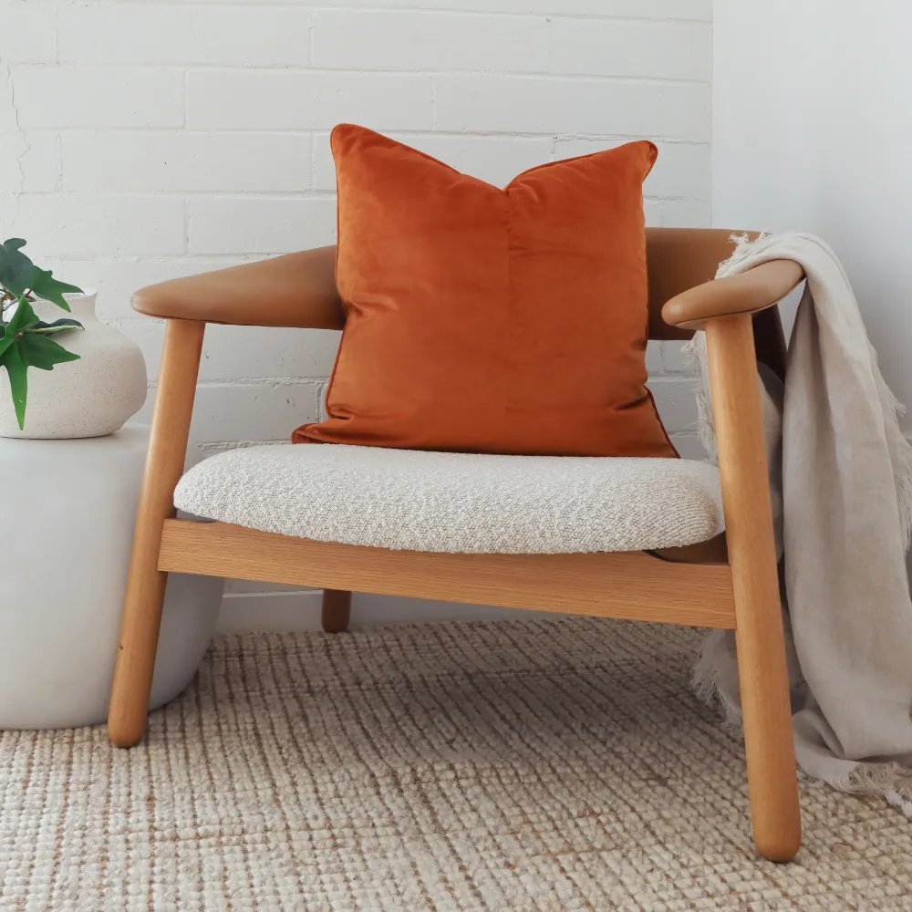 A carved wooden seat featuring an orange cushion.