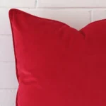 Zoomed photo of the top left corner of this red cushion cover. The image clearly shows the velvet material and large dimensions.