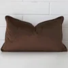 Here a chocolate brown velvet cushion is shown styled against a white wall. It has a rectangle design.
