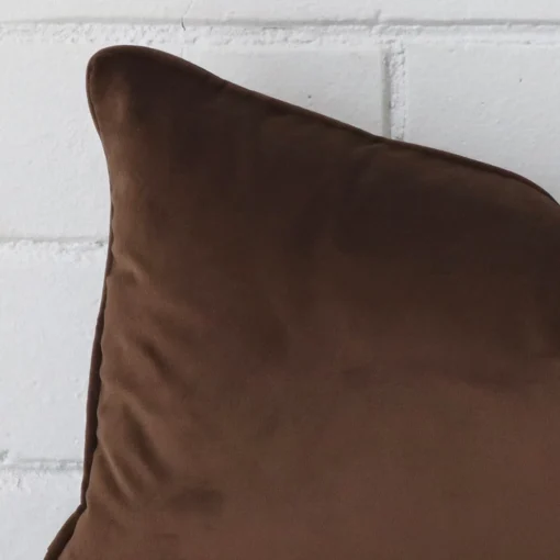 A rectangle velvet cushion positioned flat to show its seams. The chocolate brown colour is shown up close.