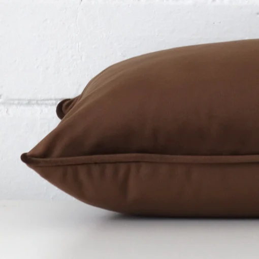 A velvet chocolate brown cushion cover shown laying on its side. It has a rectangle shape.