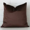Here a brown velvet cushion is shown styled against a white wall. It has a square design.