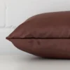 A square brown cushion cover laying flat. This viewpoint highlights the velvet fabric from a side position.