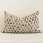Sand-coloured floral cushion cover sits against a white wall. It is constructed from a superior looking linen material and has rectangle dimensions.