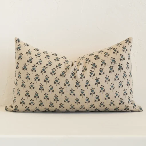 Sand-coloured floral cushion cover sits against a white wall. It is constructed from a superior looking linen material and has rectangle dimensions.
