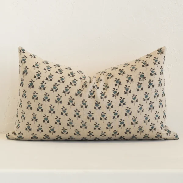 Sand-coloured floral cushion cover sits against a white wall. It is constructed from a superior looking linen material and has rectangle dimensions.