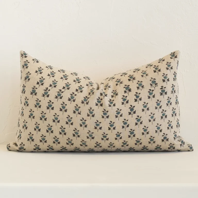 Sand-coloured floral cushion cover sits against a white wall. It is constructed from a superior looking linen material and has rectangle dimensions.