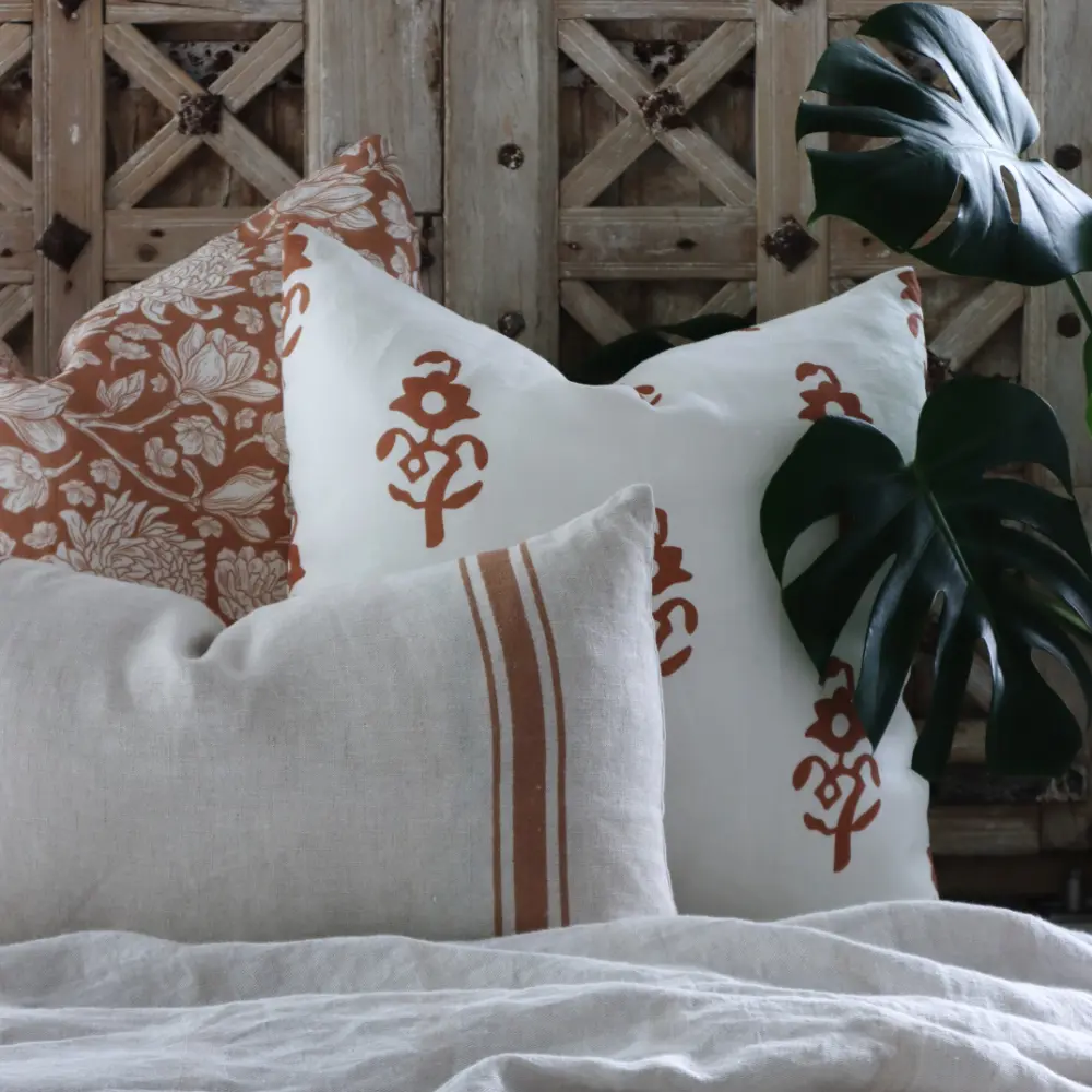 A coordinated collection of linen cushions lay on a throw on front of a wood panel.