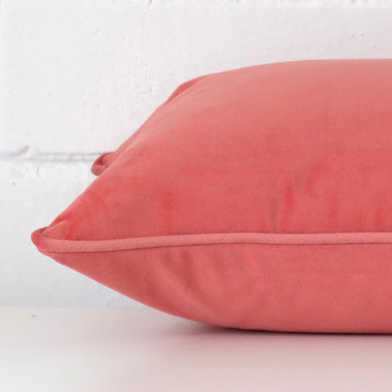 Side image of a velvet rectangle cushion cover. The design and coral colour are visible from the side showing the attachment of the panels.