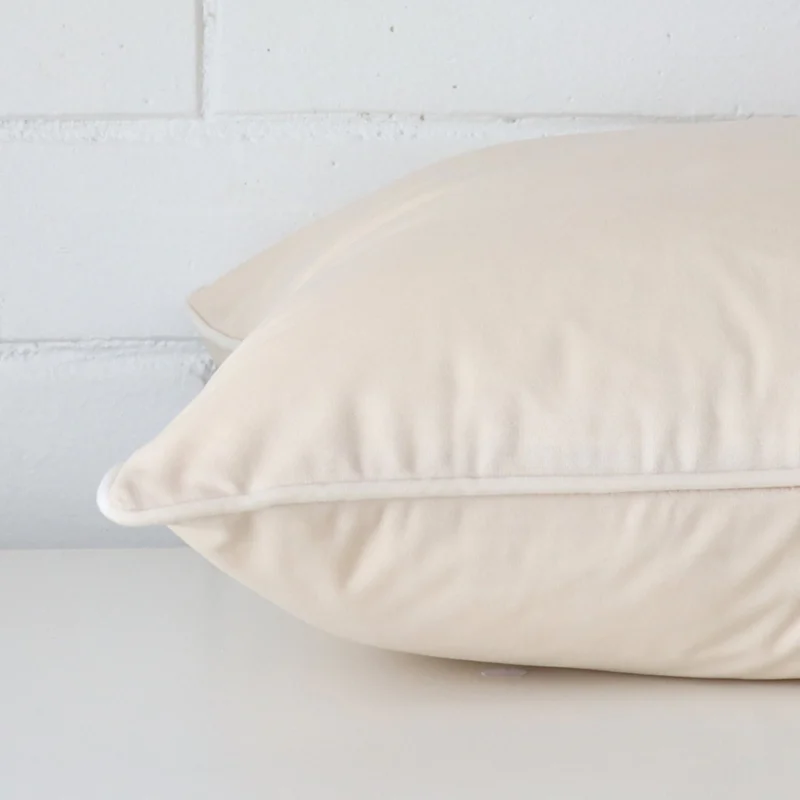 Horizontal edge view of front and back panels of velvet cushion in a large size and with cream colouring.