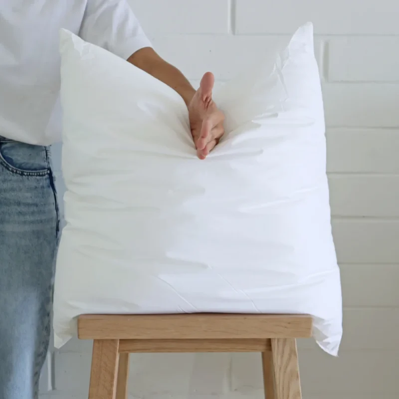 A cushion inner insert is being chopped by a hand for styling.
