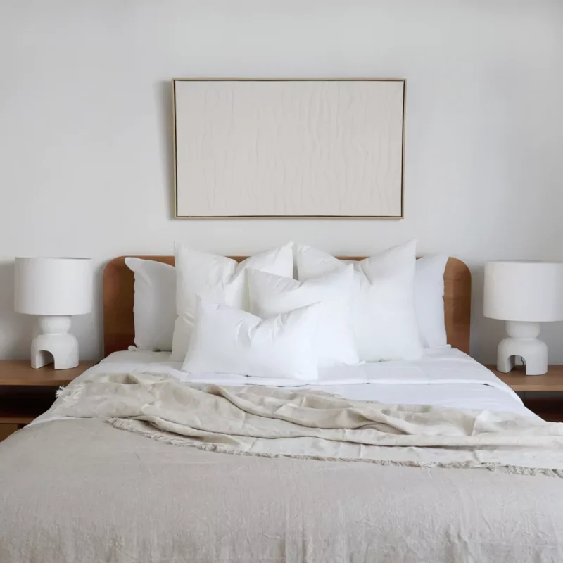 4 cushion inserts made from faux feather on a wooden bed.