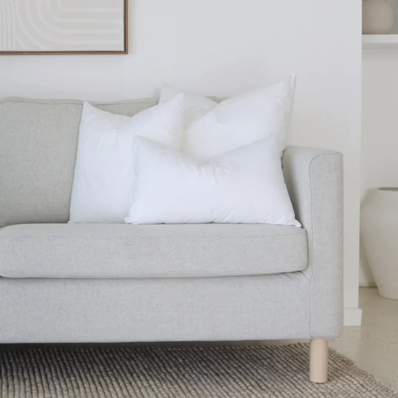 cushion-insert-faux-feather-couch-set-of-3b A set of 3 cushion inserts is arranged neatly on a corner of a grey sofa.