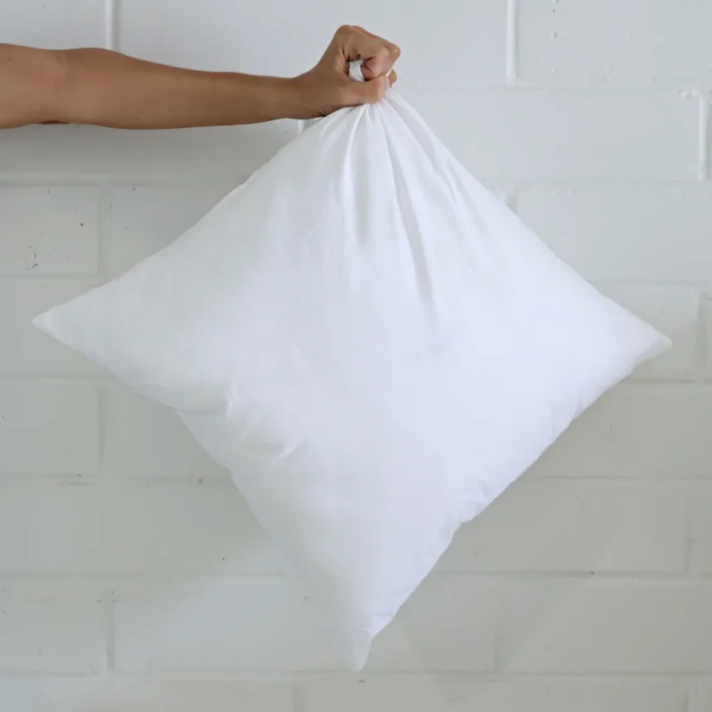 A 55x55 cushion insert inner being held out by an arm.