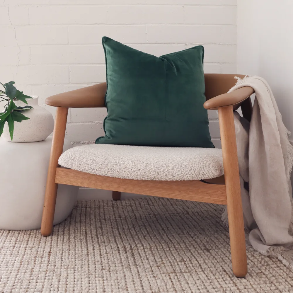 A dark frame timber chair with a green velvet cushion.