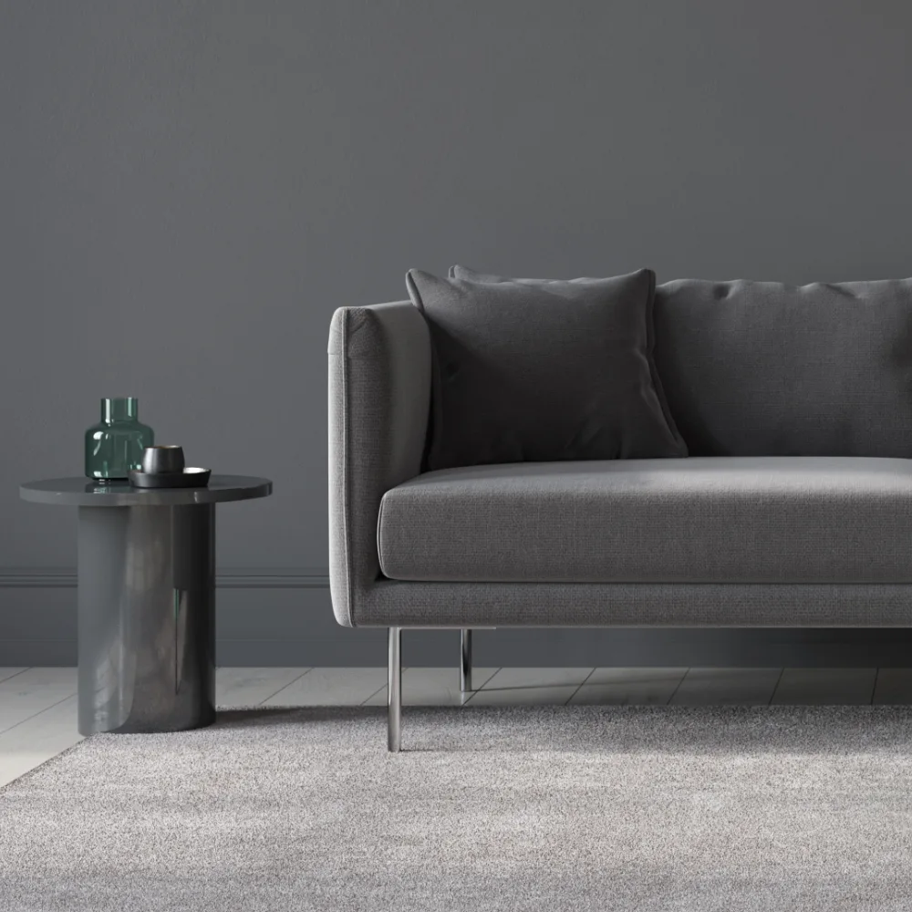 A dark simple room has an empty dark grey seat. Perfect blank canvas for cushions for a dark grey sofa.