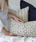A designer cushion is being placed at the front of an arrangement by a woman.