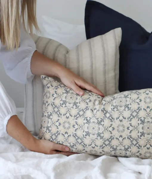 A designer cushion is being placed at the front of an arrangement by a woman.