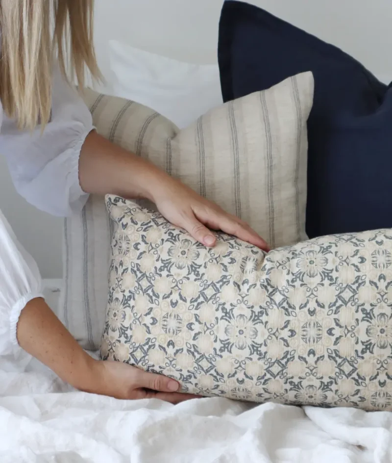 A designer cushion is being placed at the front of an arrangement by a woman.