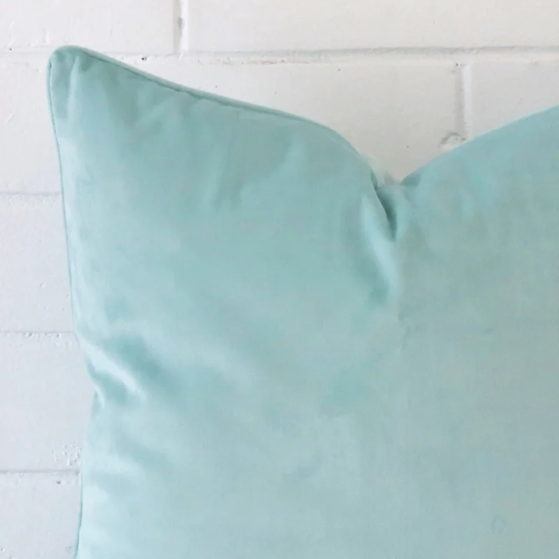 A zoomed in photo of the corner of a duck egg cushion that has velvet fabric and a large size.