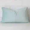 Duck egg cushion leans elegantly against a brick wall. It has been crafted from a high quality velvet material and has a square shape.